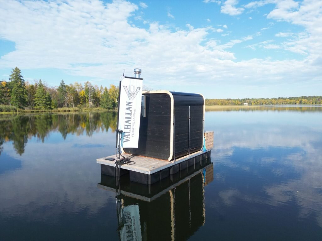 Side view of the Valhallan floating sauna showing the wood stove chimney and Valhallan banner
